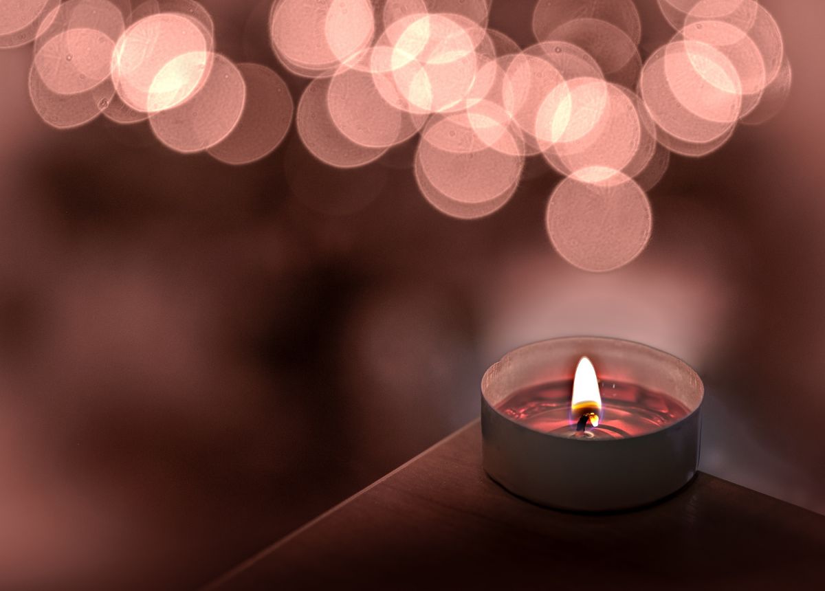 A candle on a table with a soothing bokeh background.