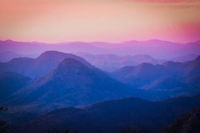 A mountain range at sunset with a pink and purple sky.