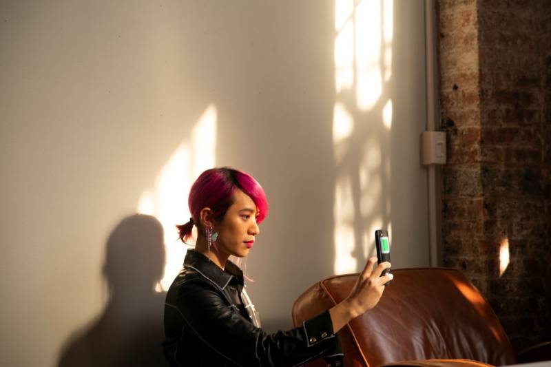 A woman with pink hair using a cell phone.