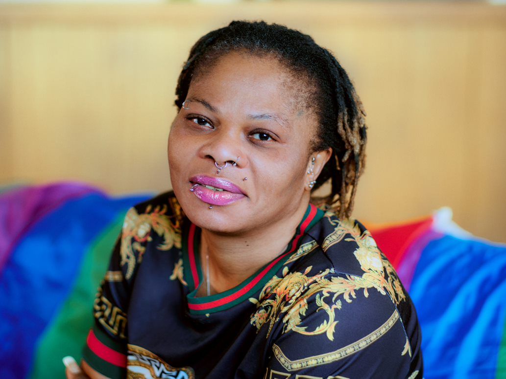 A woman with dreadlocks sitting on a colorful couch.