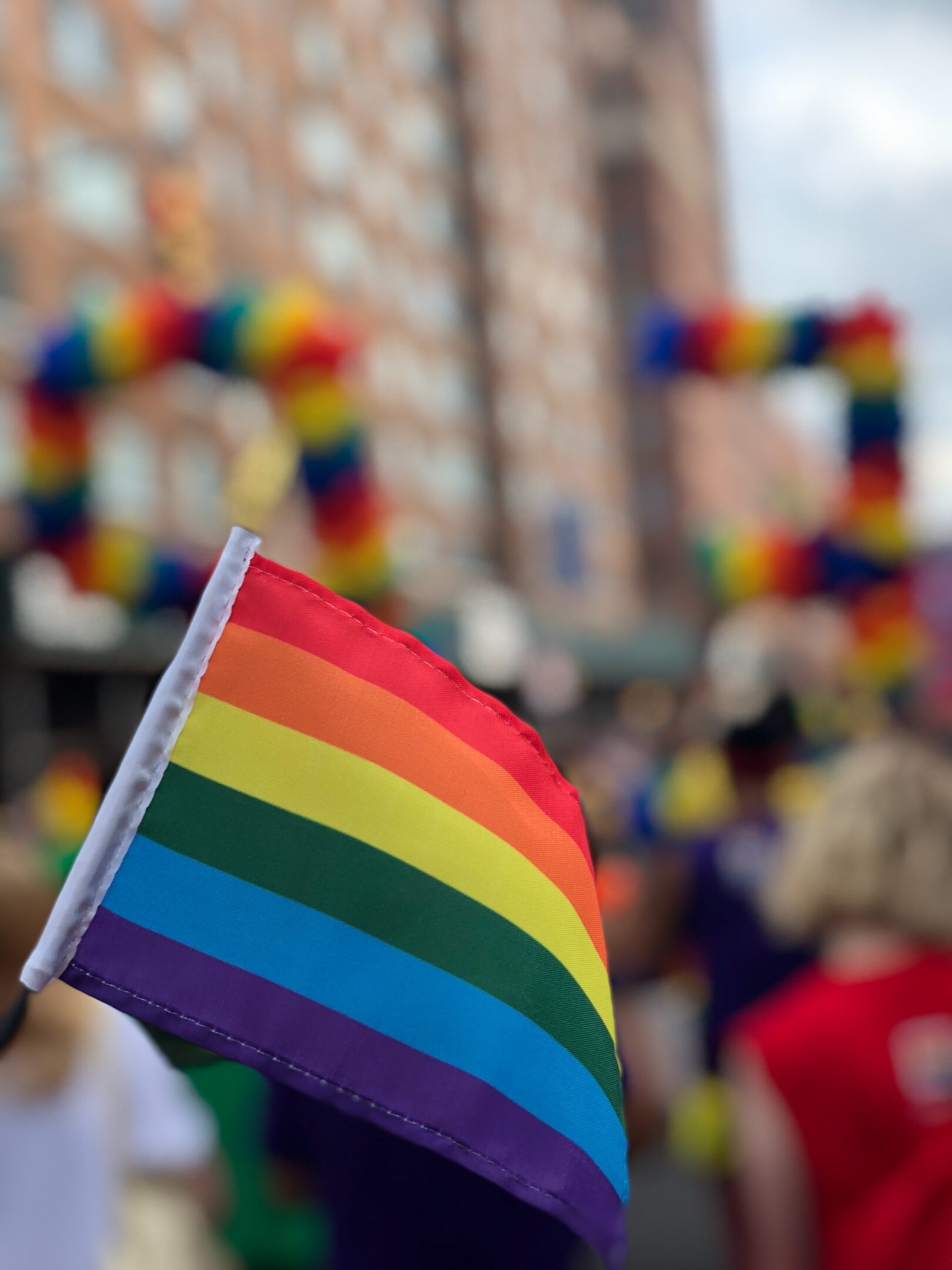 A group of people holding a rainbow flag in a parade.