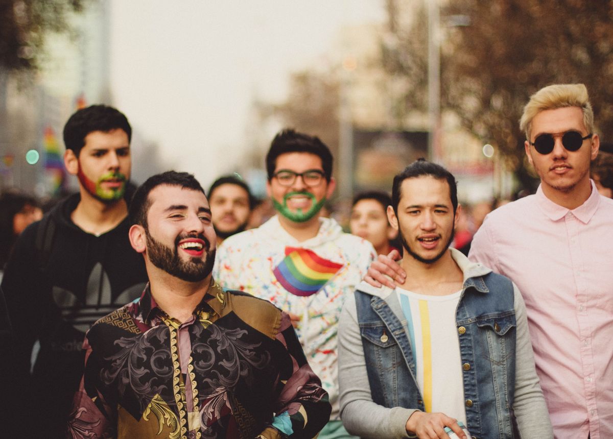 A group of men dressed up in rainbow paint on a street.