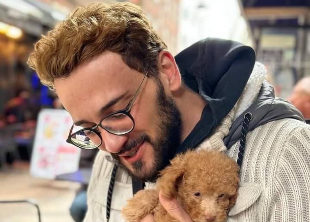Man with glasses holding a poodle, starring in manono's story.