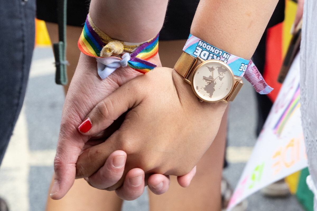 Two people holding hands at a pride parade.