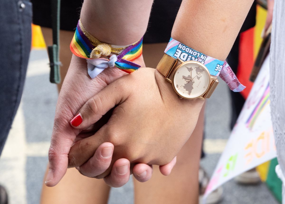 Two people holding hands at a pride parade.