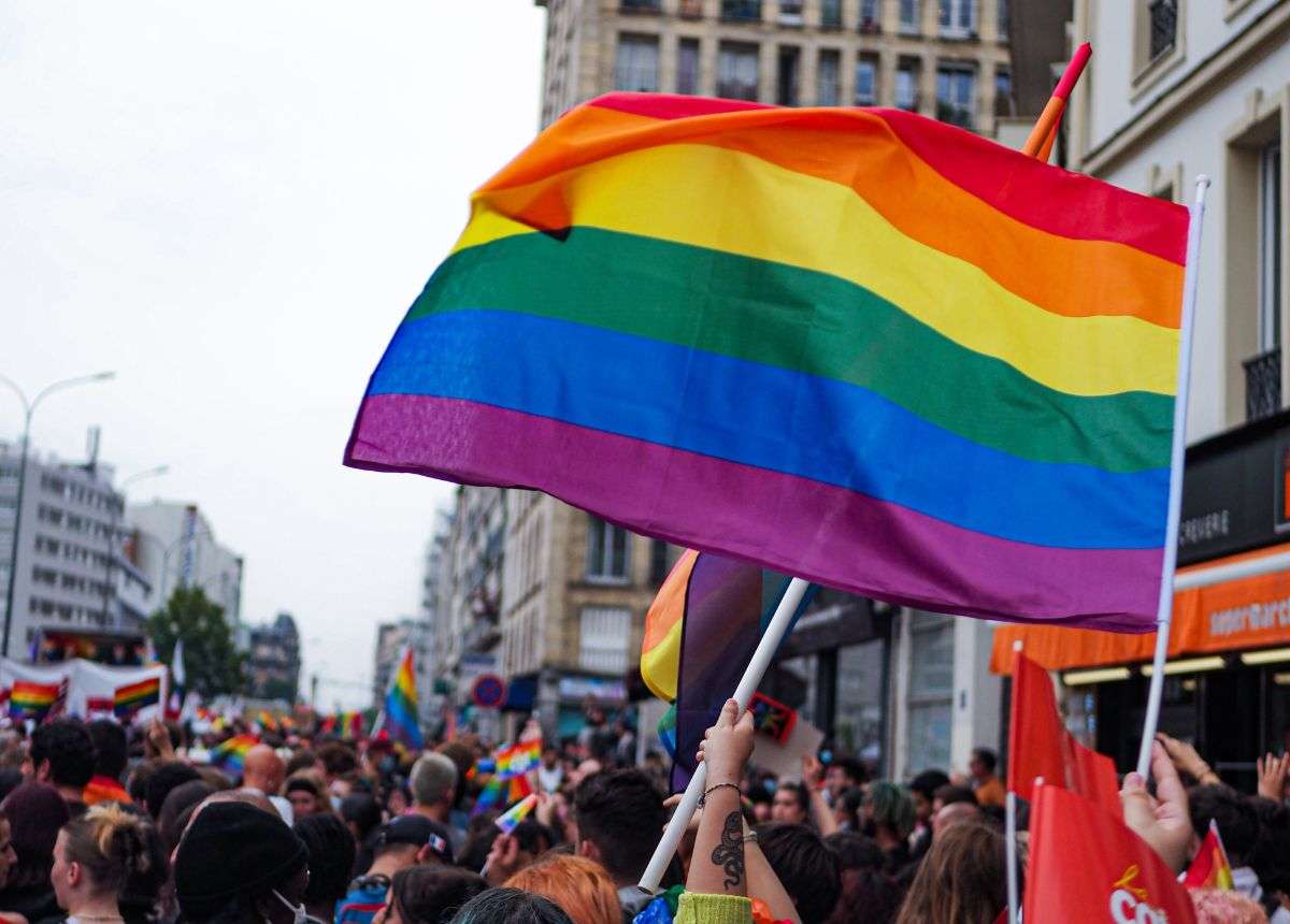A group of people waving a rainbow flag in a city.