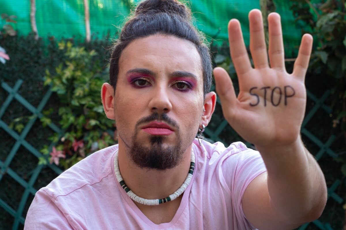 queer person showing a 'stop' on their hand